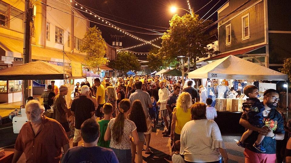 A busy local street market at night — the whole community out together